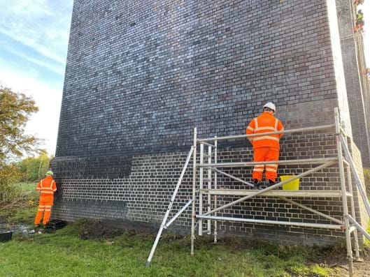 Crigglestone Viaduct - workers in protective clothing and hard hats stand on scaffold to re-point the bridge.
